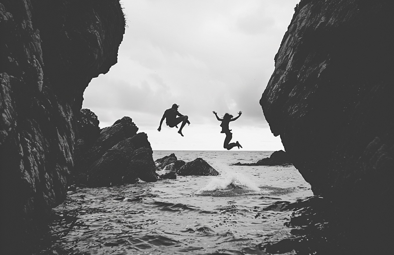 People jumping off cliff in black and white